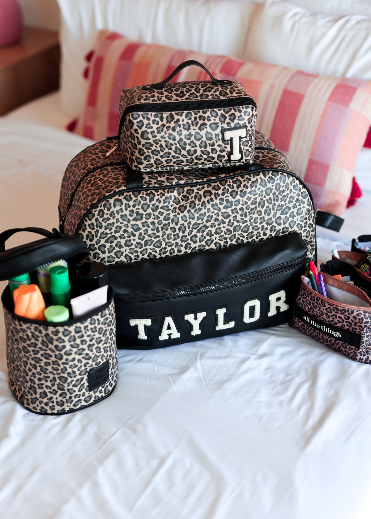 Leopard print duffle and accessories on a bed