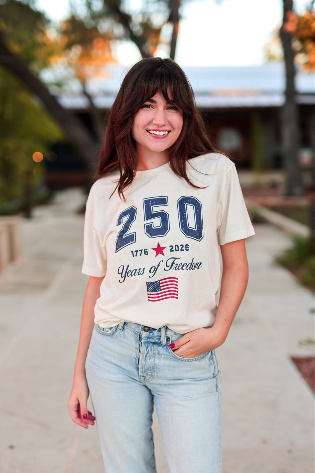 Woman wearing a t-shirt with '250 Years of Freedom' text and design, standing outdoors.