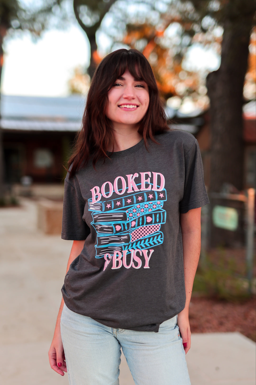 Woman wearing a 'Booked & Busy' t-shirt outdoors