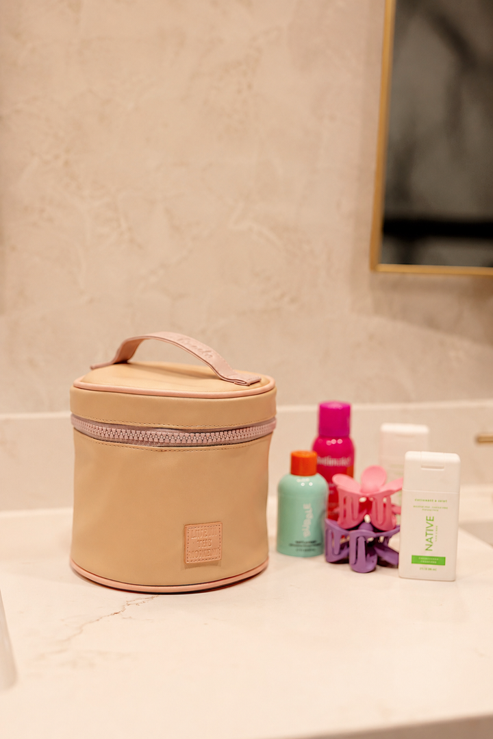 Beige cosmetic bag on a bathroom counter with various products