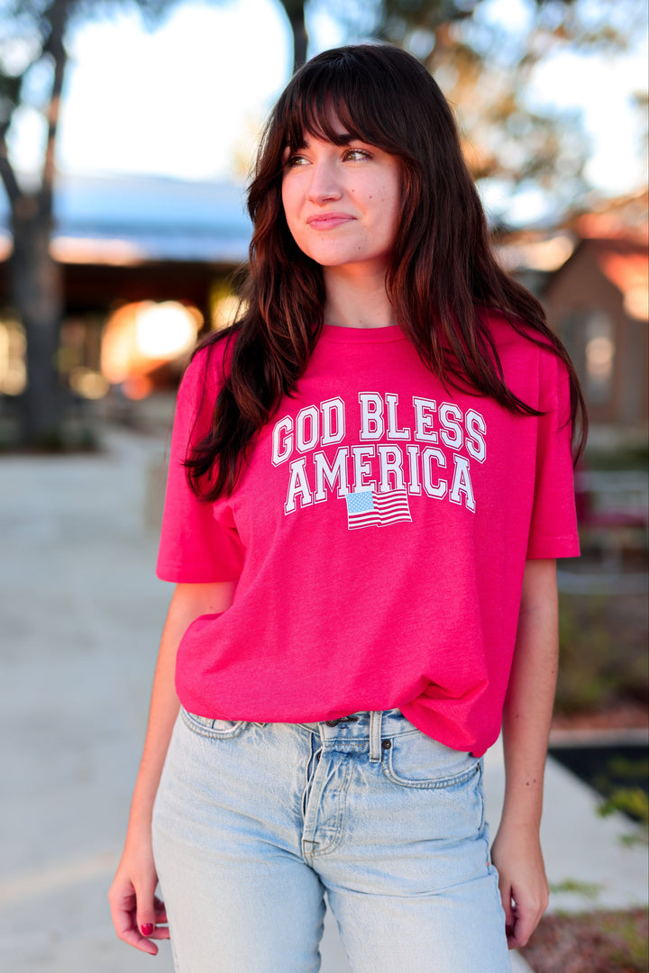 Person wearing a red 'God Bless America' t-shirt outdoors.
