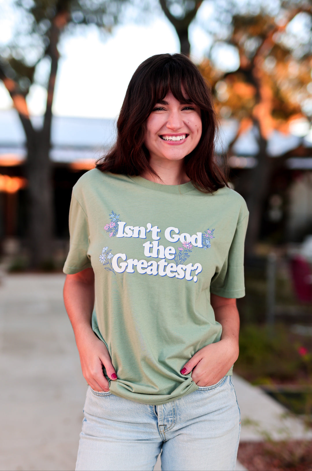Woman wearing a green t-shirt with text, standing outdoors.