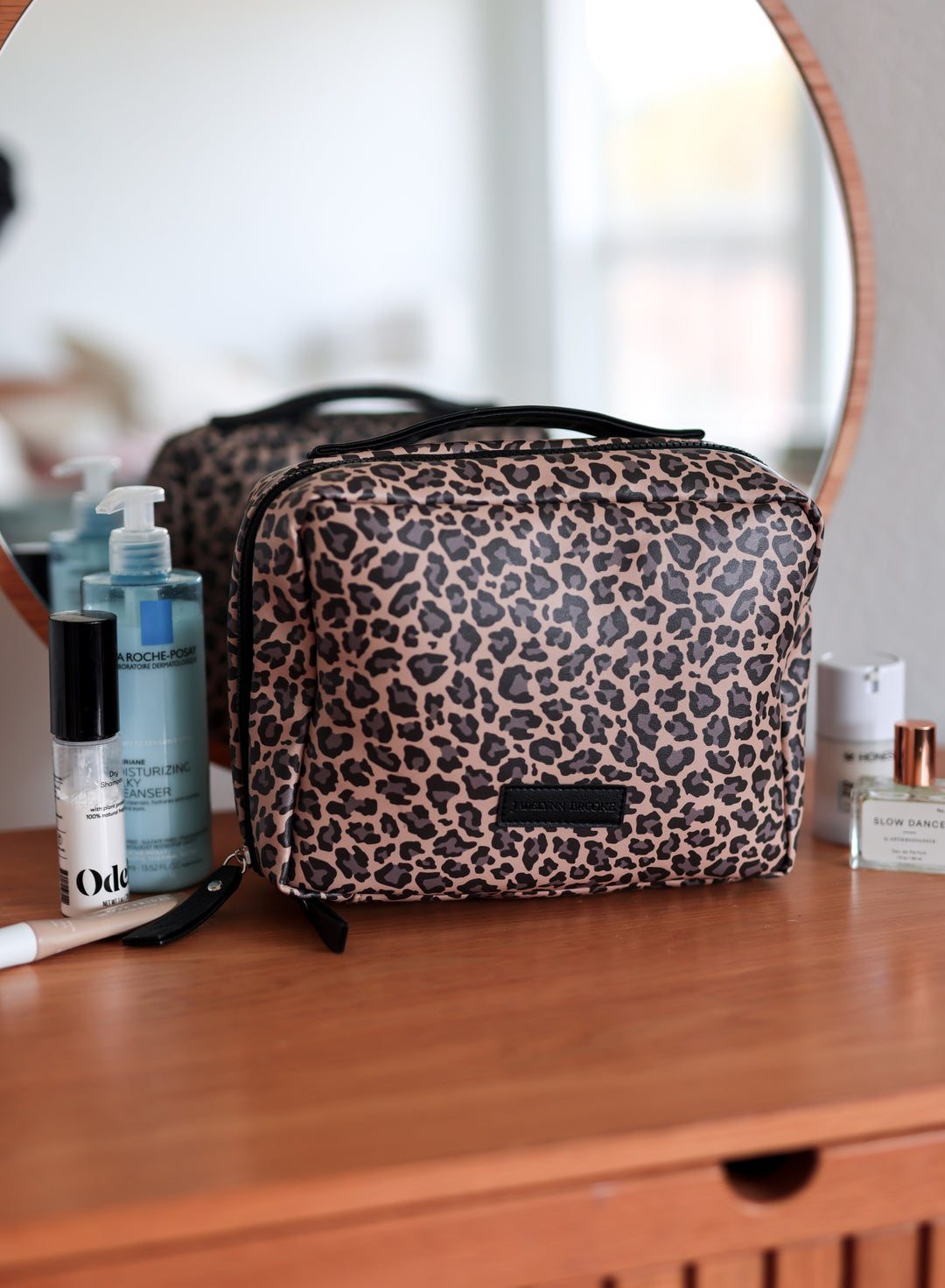 Leopard print cosmetic bag on a wooden surface with blurred background