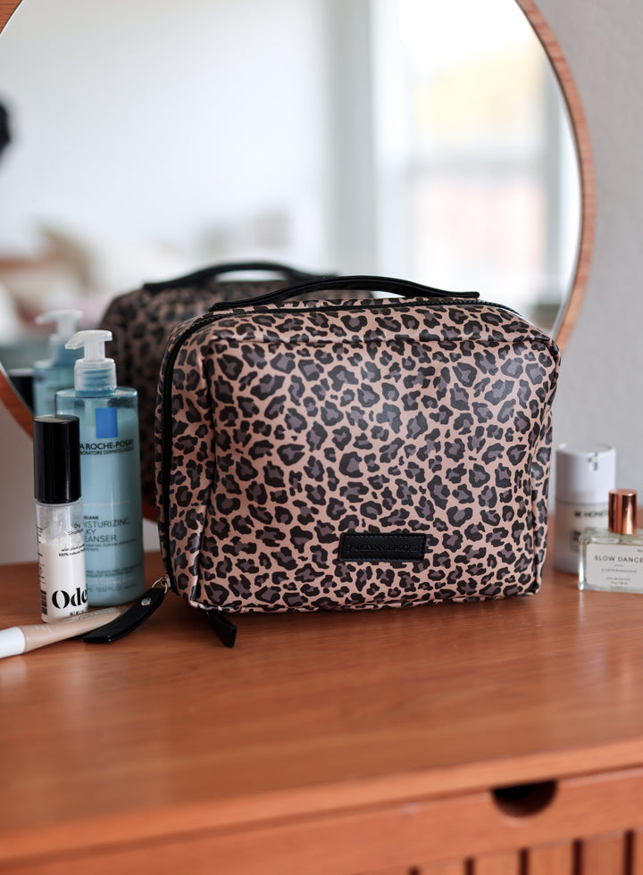 Leopard print cosmetic bag on a wooden surface with blurred background