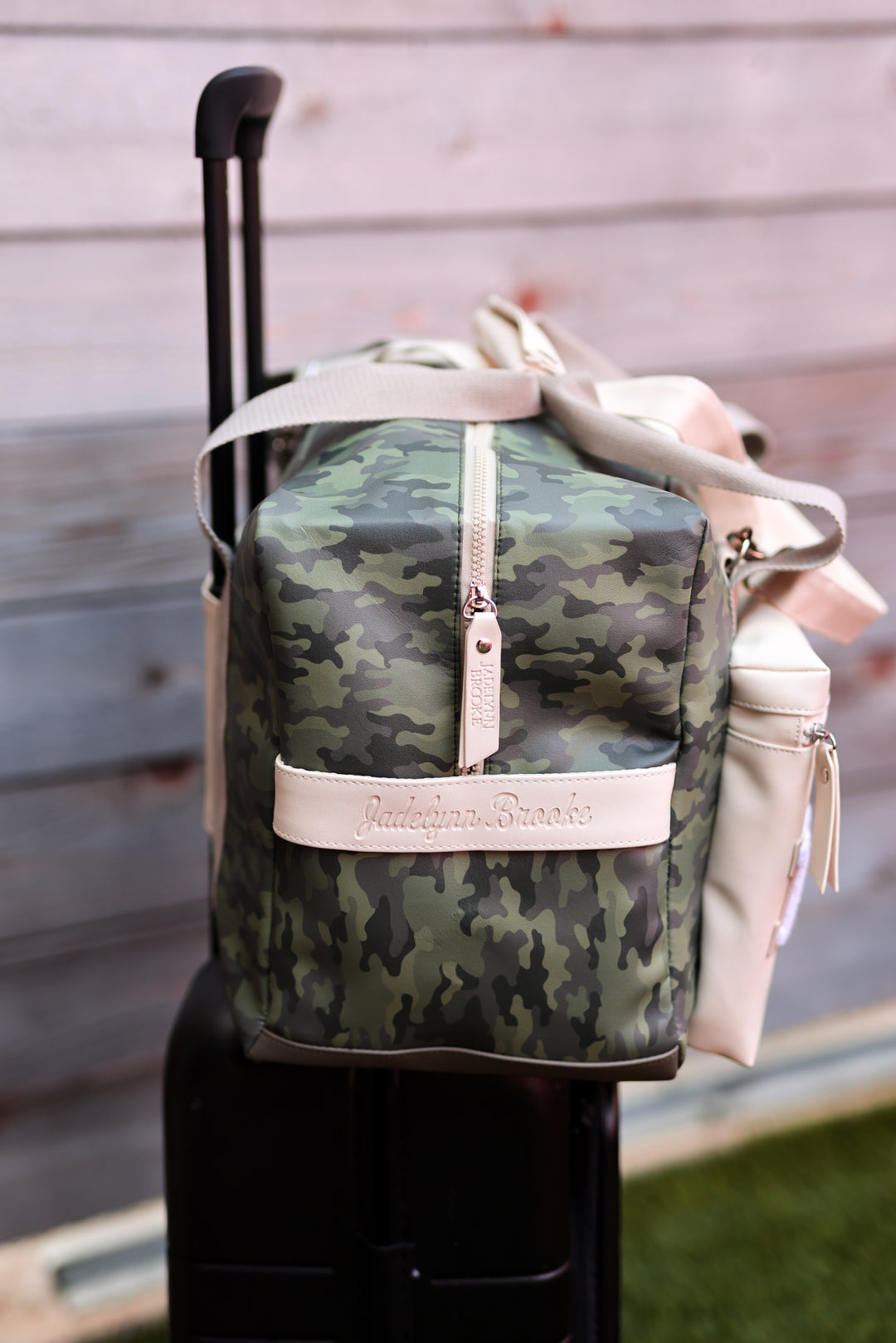 Green camouflage duffel bag with beige accents and zipper, perfect for travel and stylish adventures.
