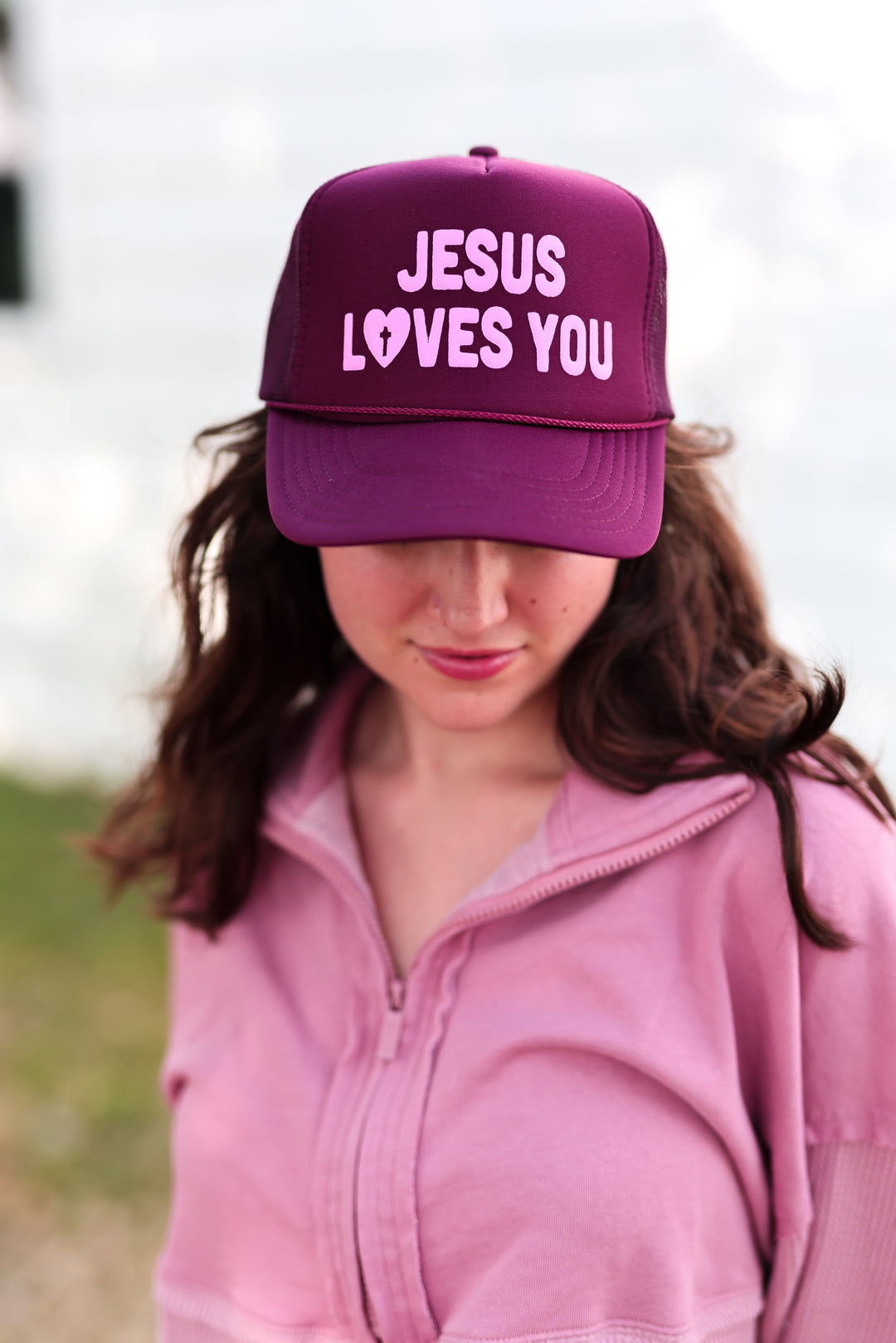 Maroon trucker hat with 'Jesus Loves You' text, perfect for casual wear and Christian themed outfits.