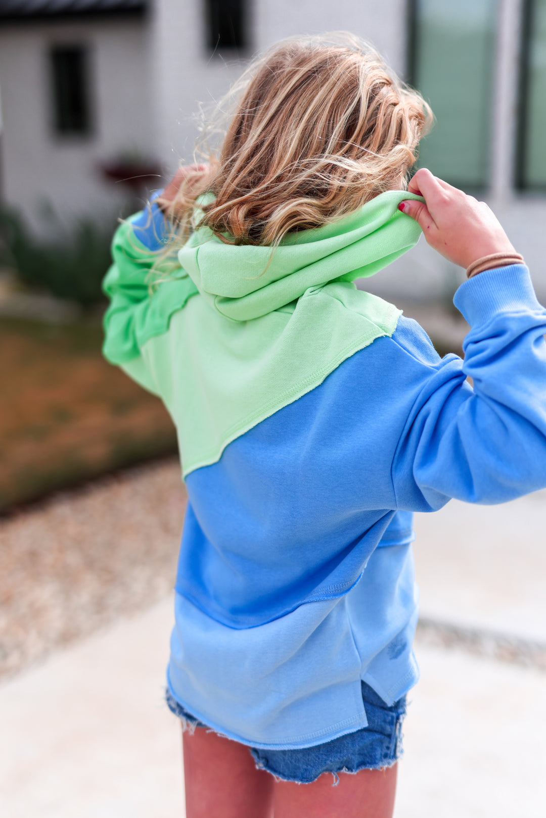 Girl in a color-blocked hoodie featuring blue and green hues, perfect for casual wear and outdoor activities.