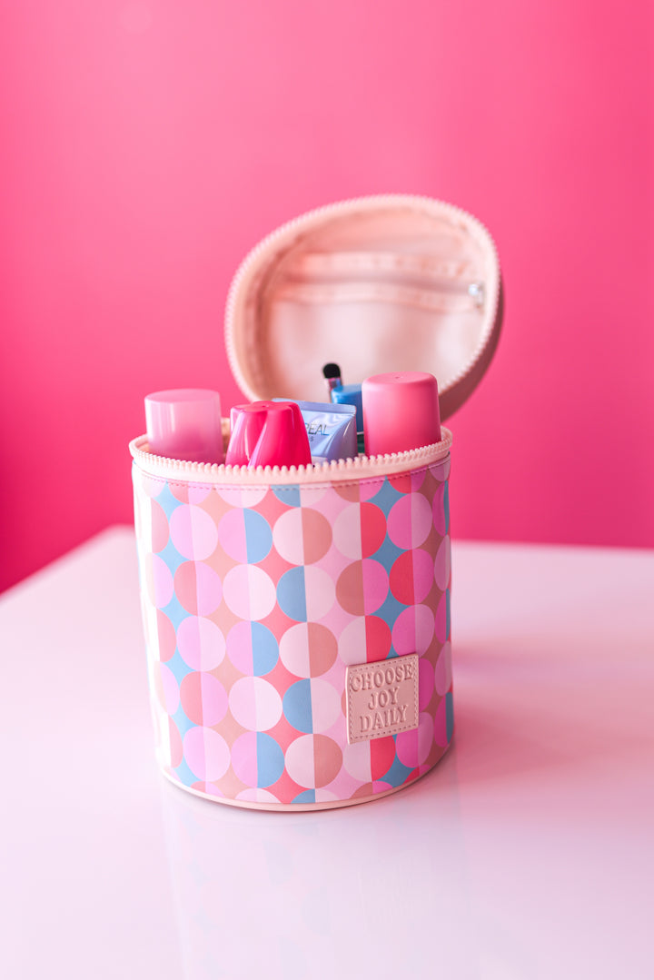 Colorful circular patterned cosmetic bag with zip, storing pink beauty products and creams.