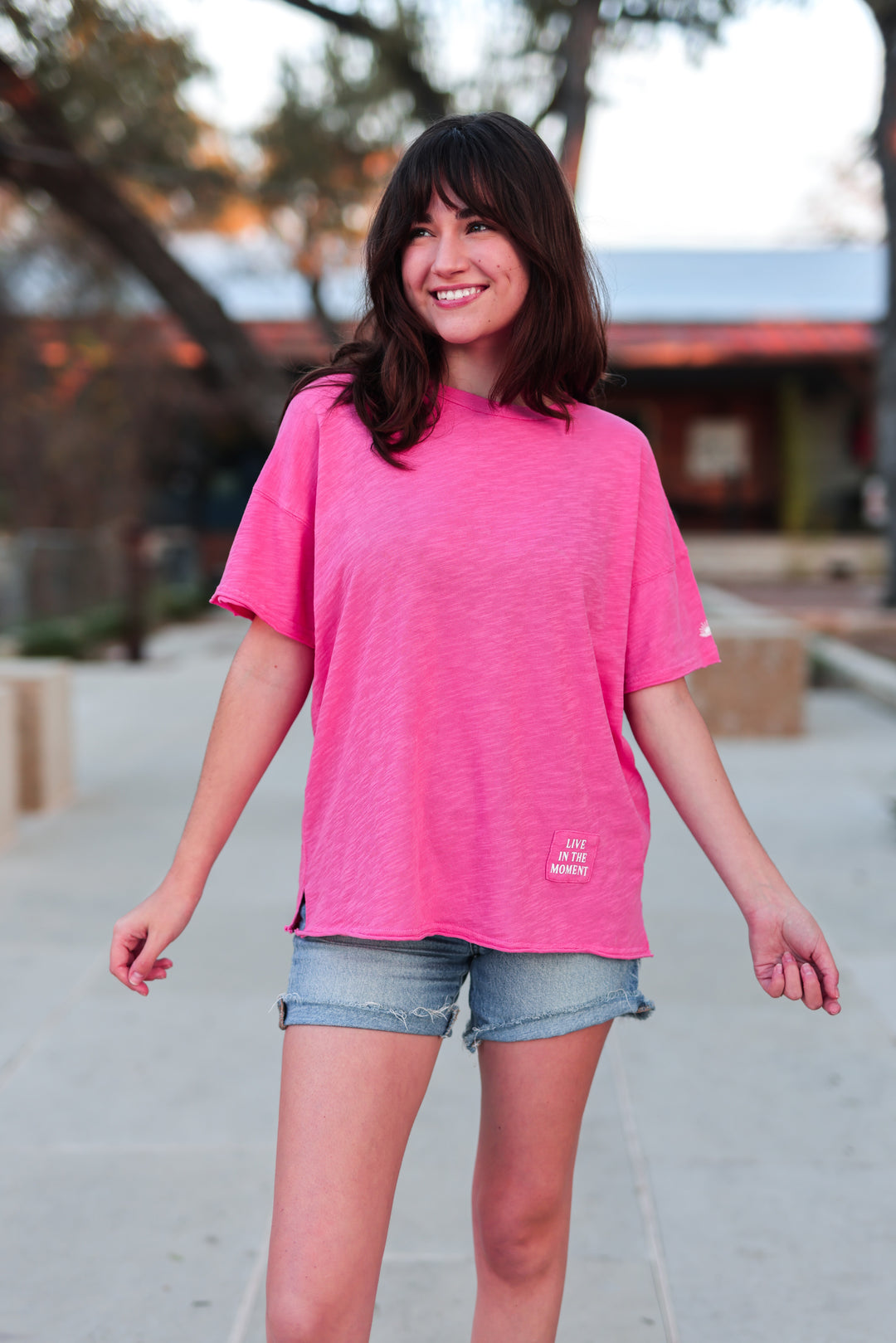Women's pink oversized t-shirt made of soft fabric featuring 'Live in the Moment' graphic.