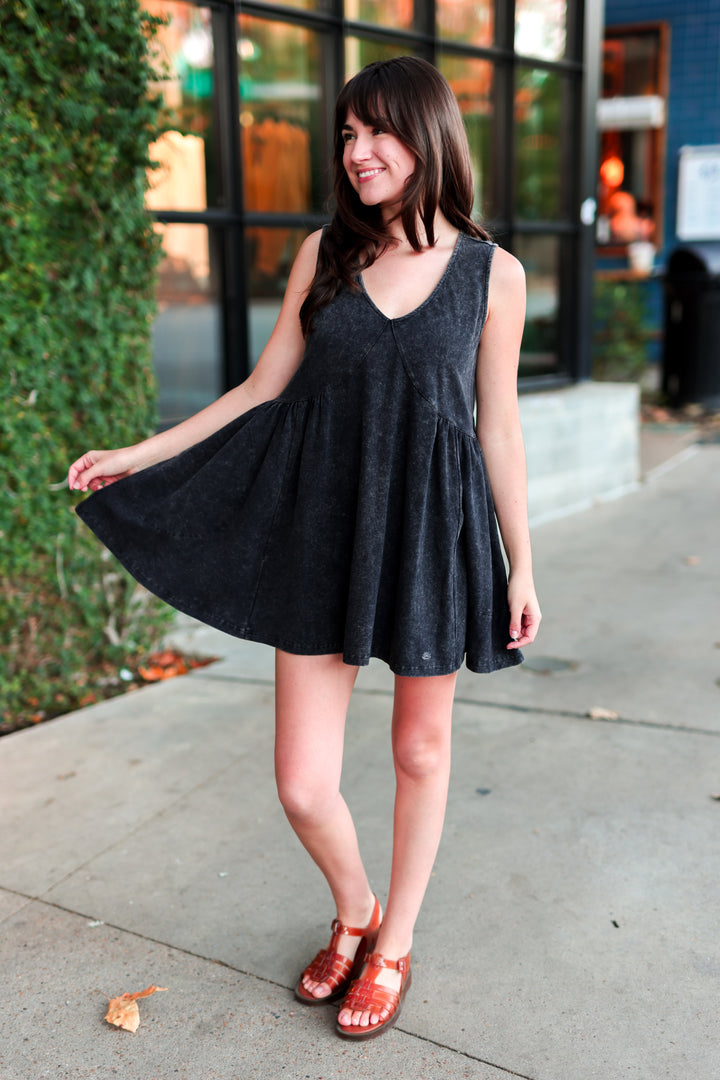 Woman in flowy black dress standing outside.