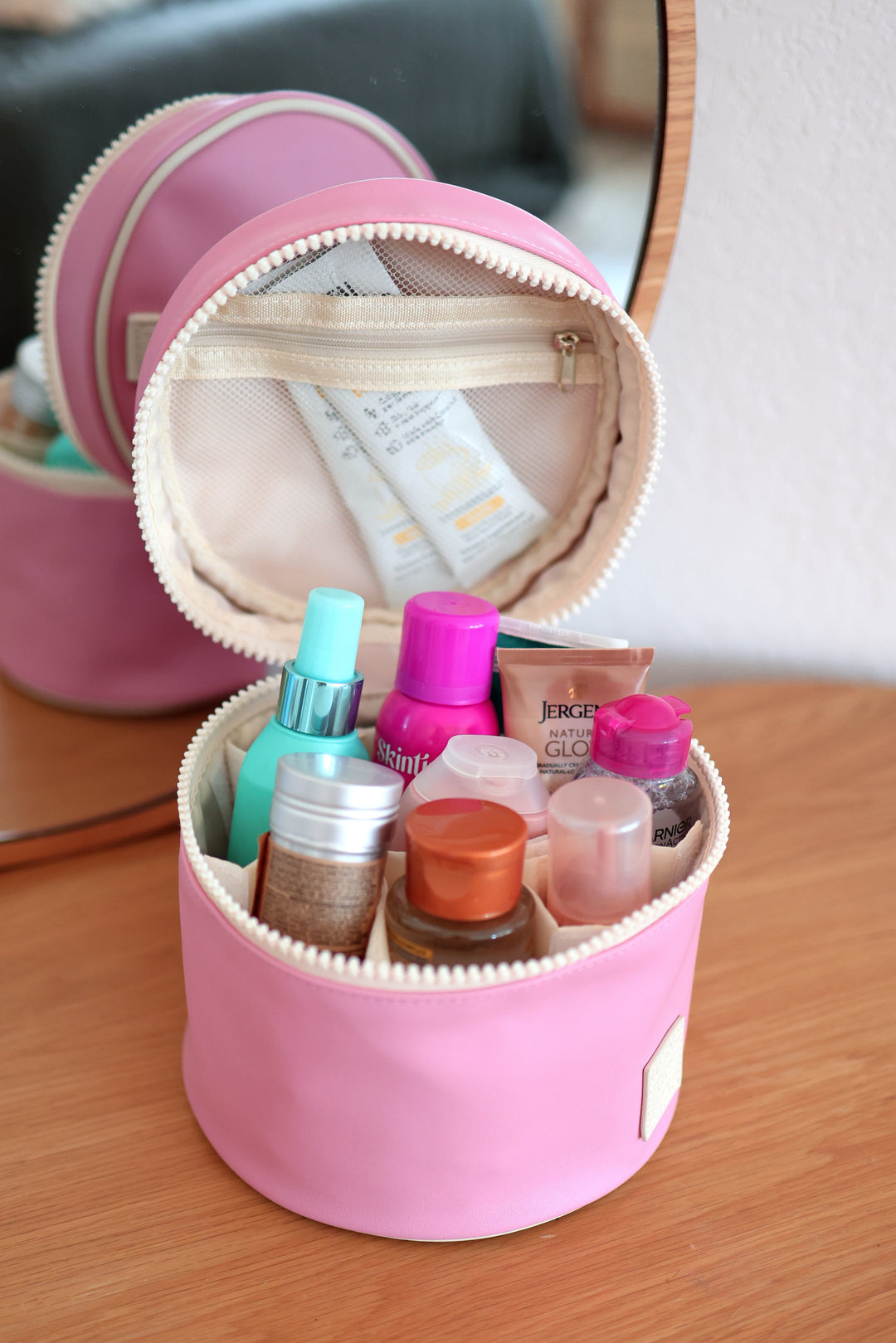 Pink makeup organizer with various cosmetic products on a wooden surface