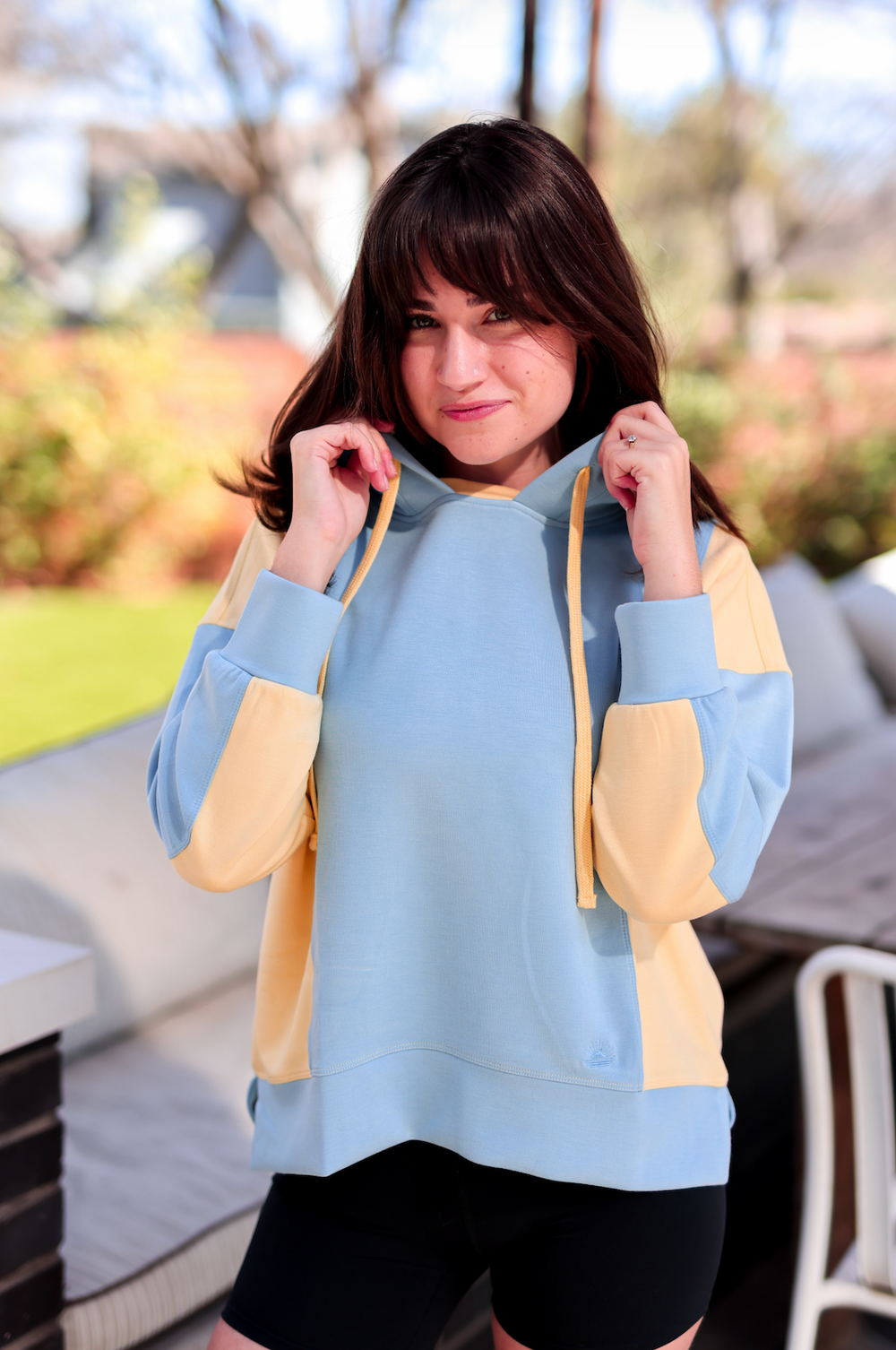 Casual two-tone hoodie in blue and yellow, lightweight fabric, with adjustable drawstring and relaxed fit.