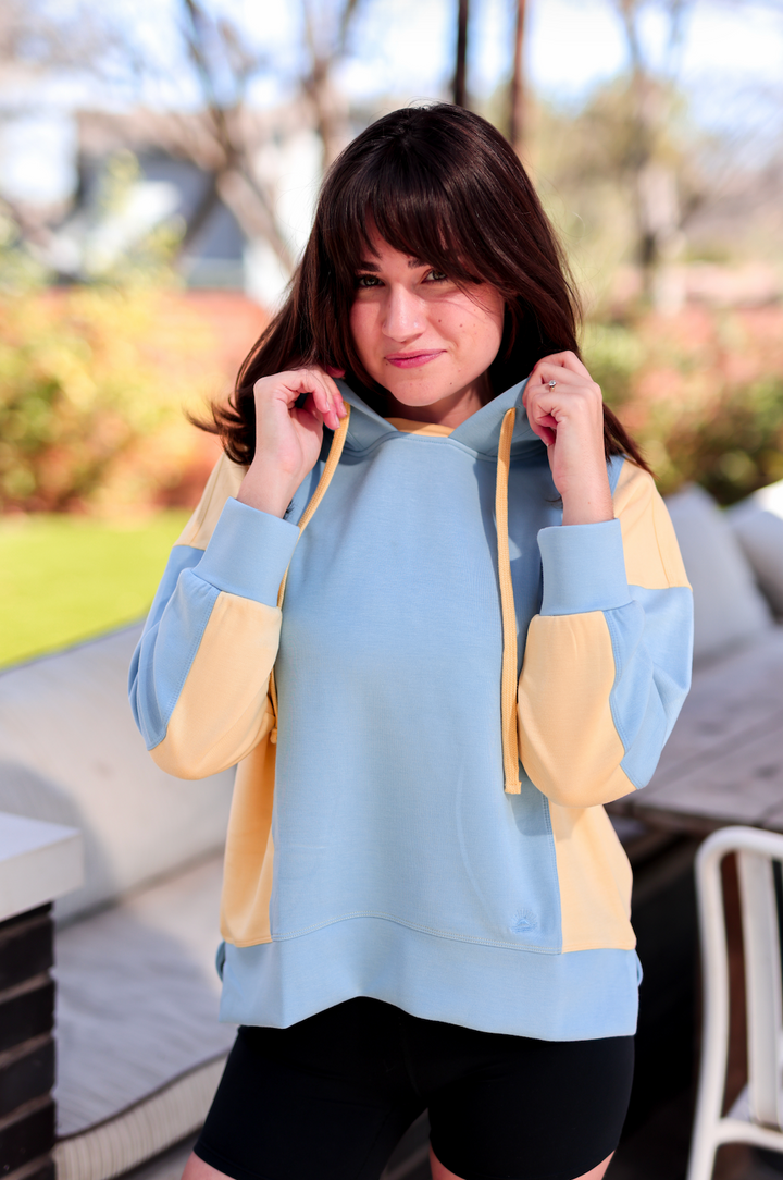 Casual two-tone hoodie in blue and yellow, lightweight fabric, with adjustable drawstring and relaxed fit.