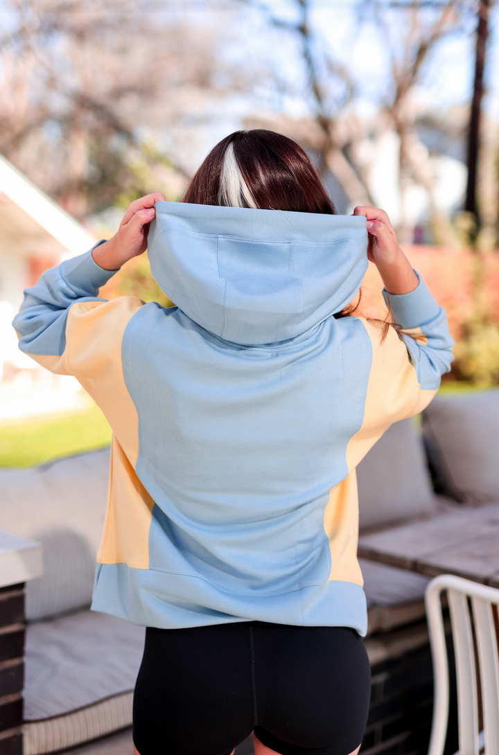 Back view of a stylish blue and yellow hoodie made of soft material, perfect for casual wear.