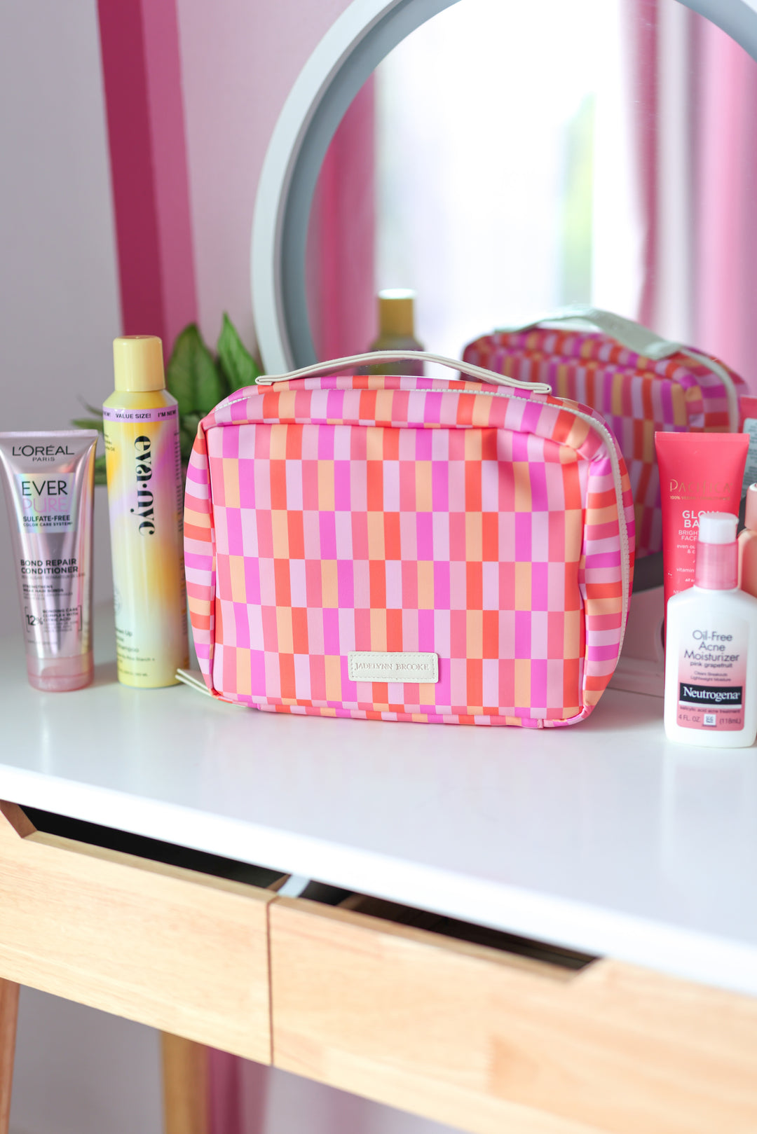 Colorful pink and orange striped makeup bag with zipper, perfect for organizing cosmetics and toiletries.
