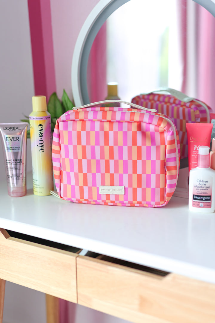Colorful pink and orange striped makeup bag with zipper, perfect for organizing cosmetics and toiletries.