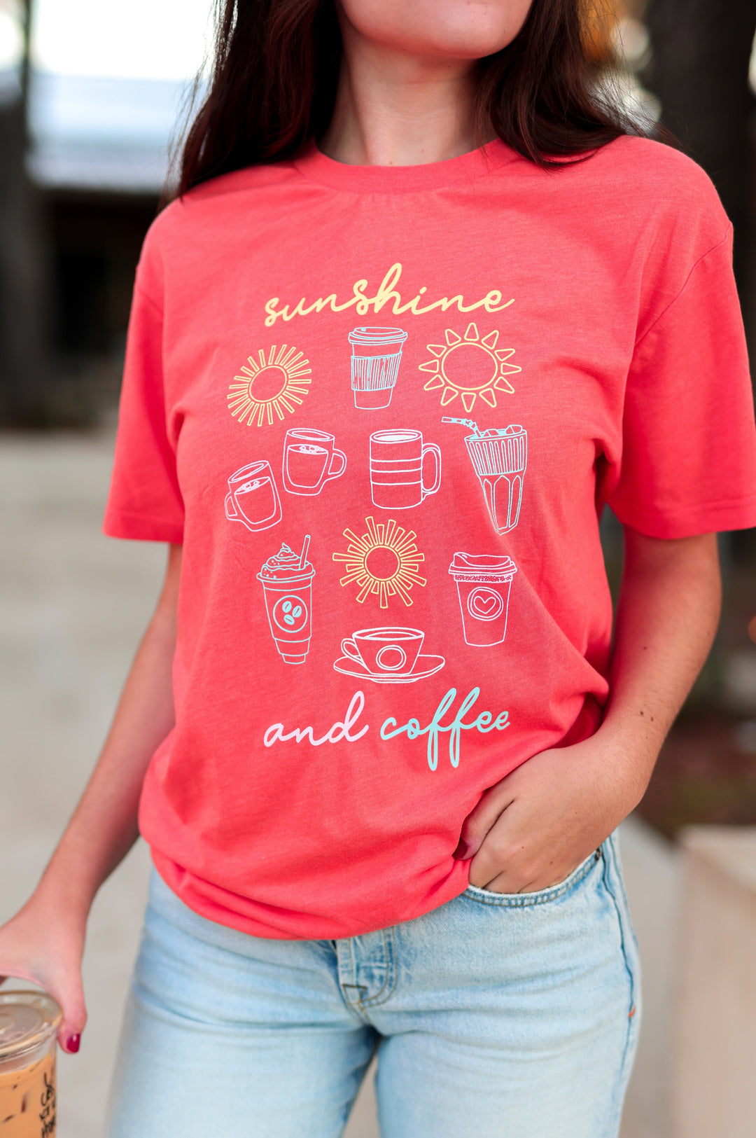 Person wearing a orange t-shirt with 'sunshine and coffee' design, holding a coffee cup.