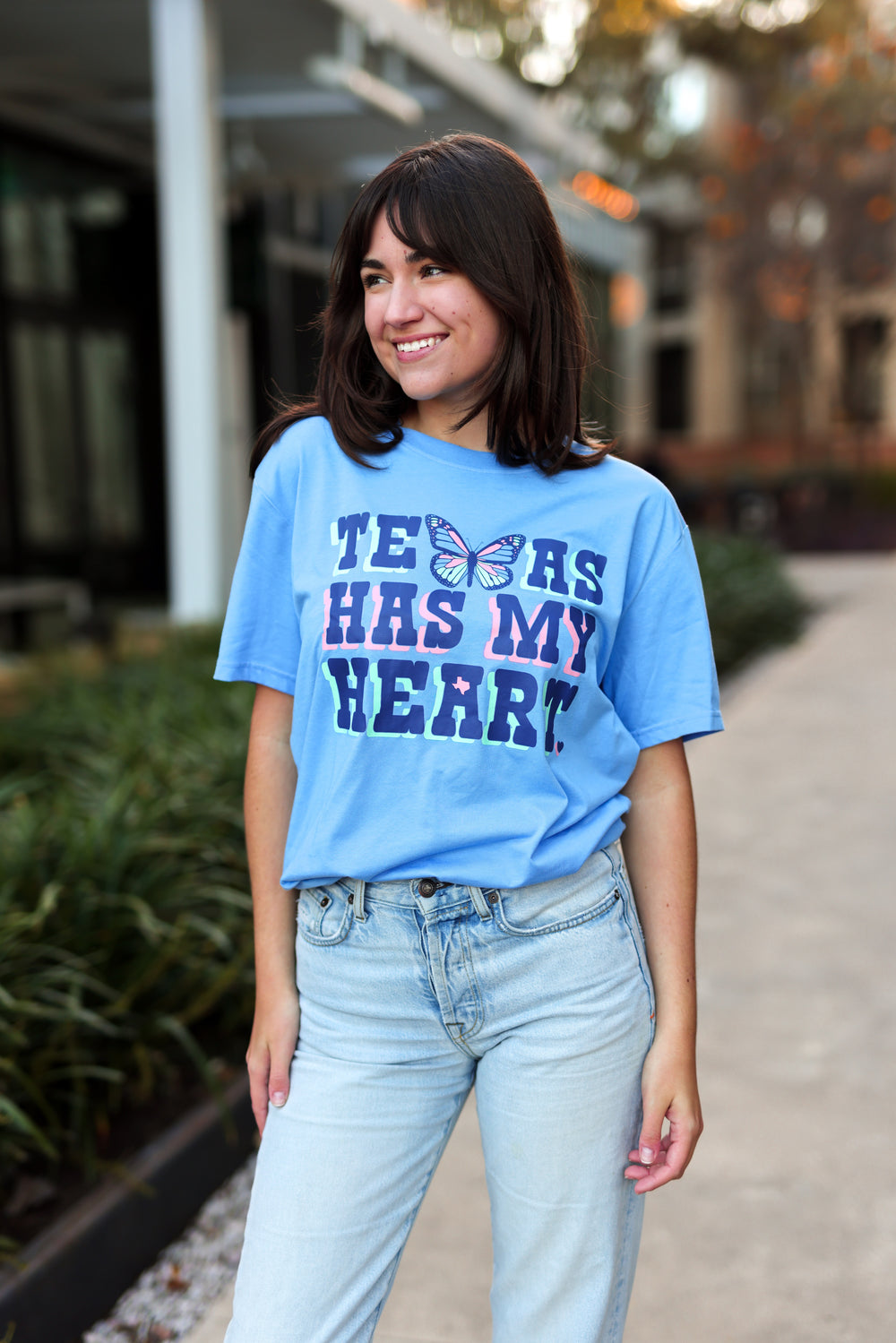 Person wearing a blue t-shirt with text standing outdoors.