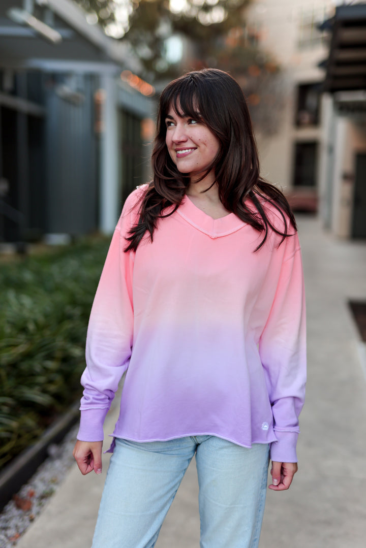 Woman wearing a gradient pink and purple sweater outdoors