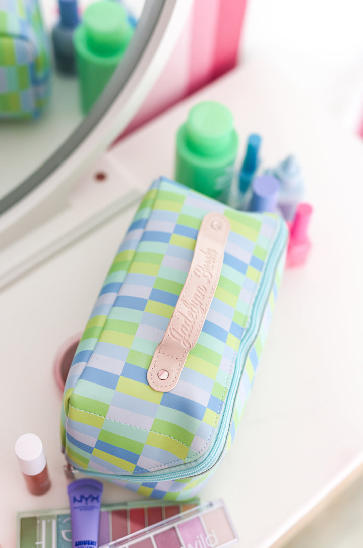 Colorful plaid makeup bag in blue and green, featuring a leather name tag and zipper closure, ideal for cosmetics.