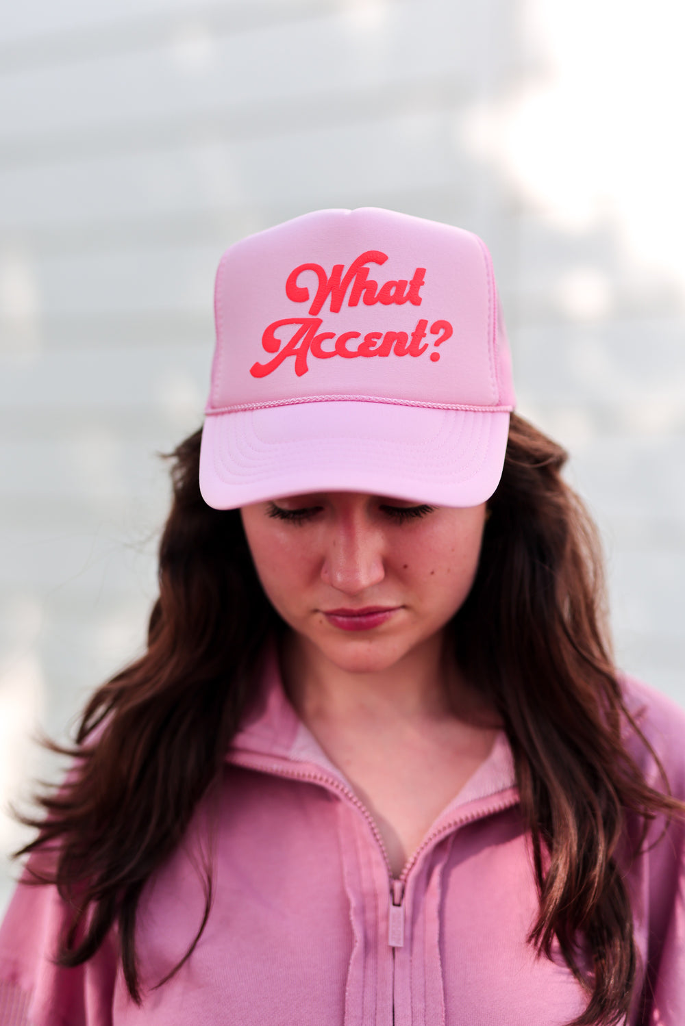 Pink trucker hat with 'What Accent?' text, perfect for casual style and fun outfits.