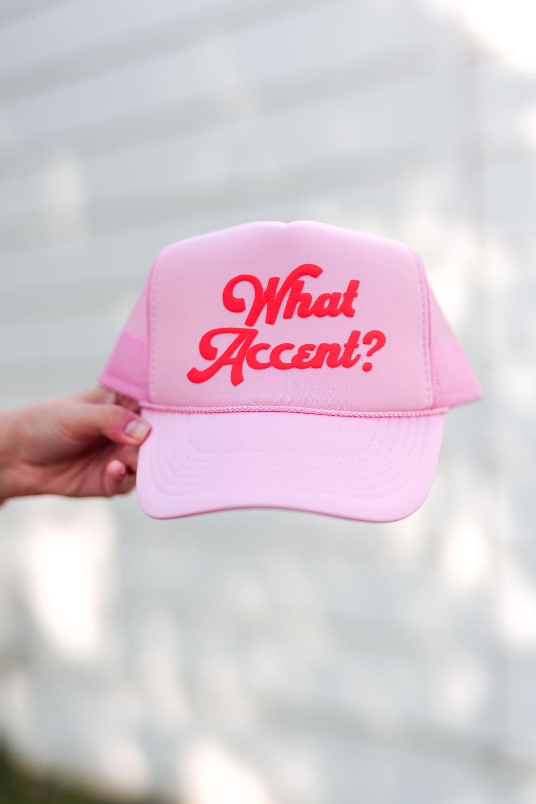 Pink trucker hat featuring playful 'What Accent?' text, perfect for casual outings and summer wear.