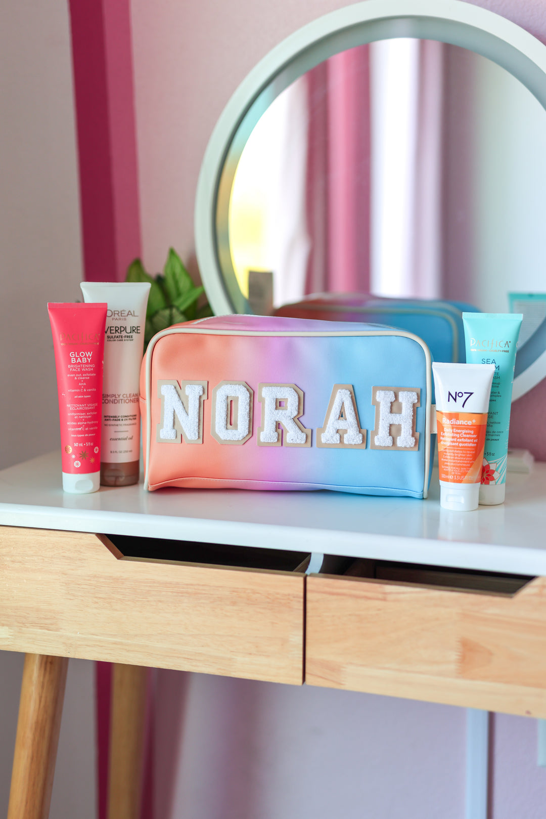 Colorful makeup bag with 'NORAH' branding on a vanity table with cosmetic products.