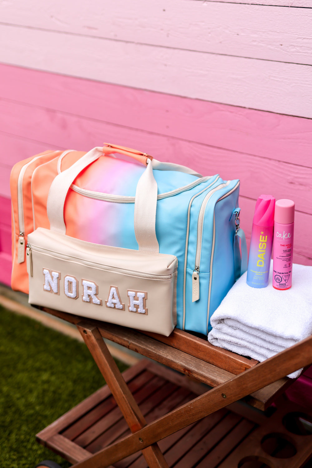 Colorful bags and items on a wooden cart against a pink and white striped background