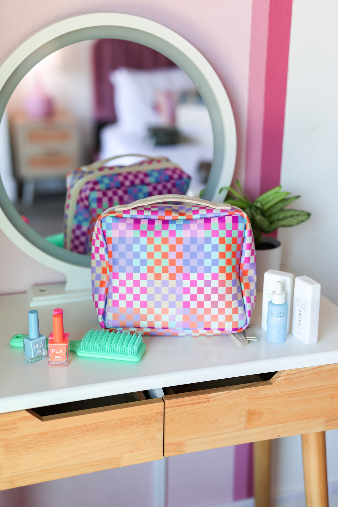 Colorful checkered makeup bag on a vanity with various items.