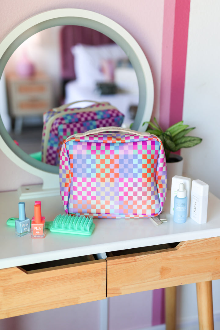 Colorful checkered makeup bag on a vanity with various items.