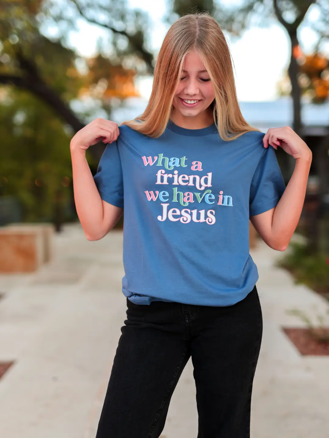 Person wearing a blue t-shirt with colorful text outdoors